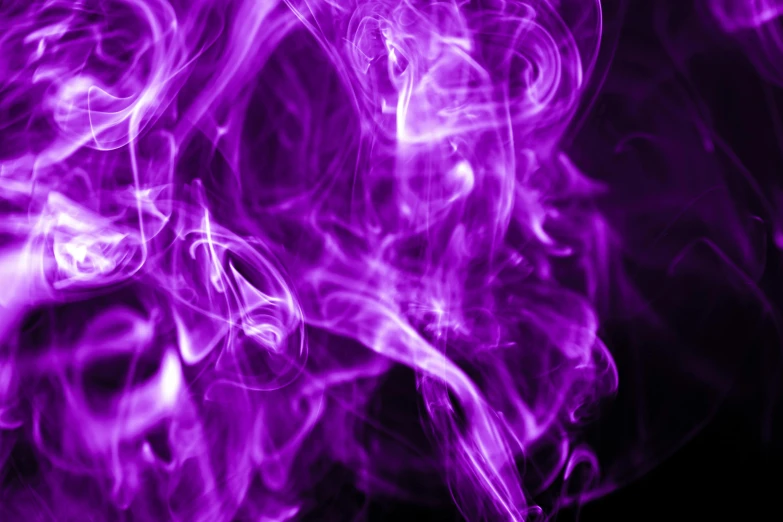 some purple smoke is moving across a dark surface