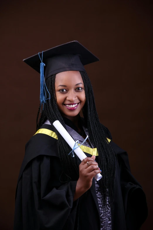 a smiling  wearing graduation gown and a hat