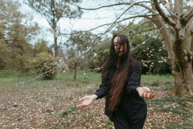 a woman is dressed in black and walking through the grass