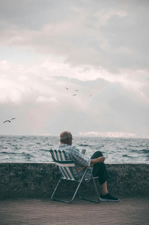 a person sits in a lawn chair looking out over a body of water