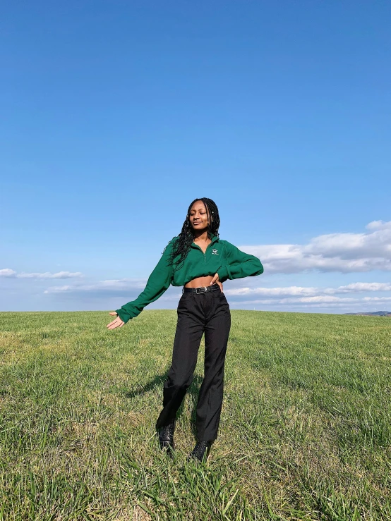 a woman in the middle of a field of grass, standing on one leg