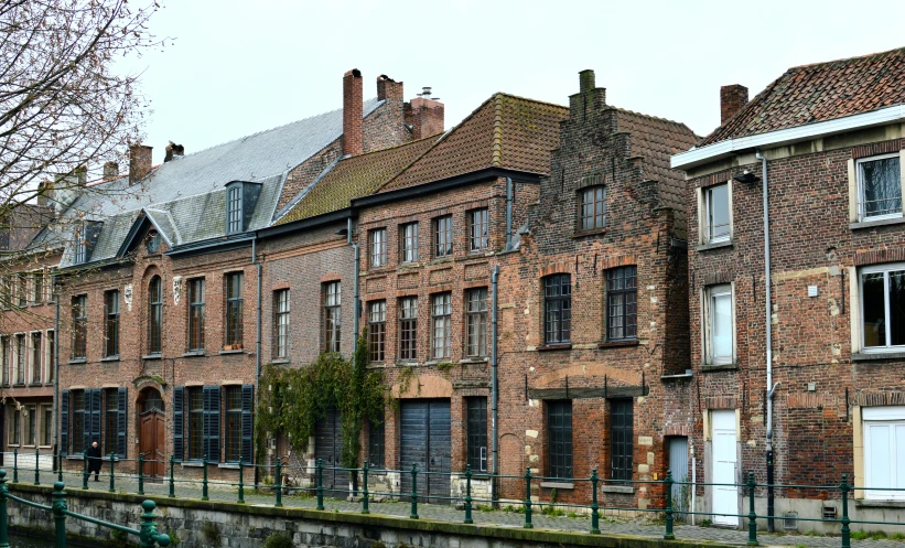 an old brick building on the side of a river with lots of windows