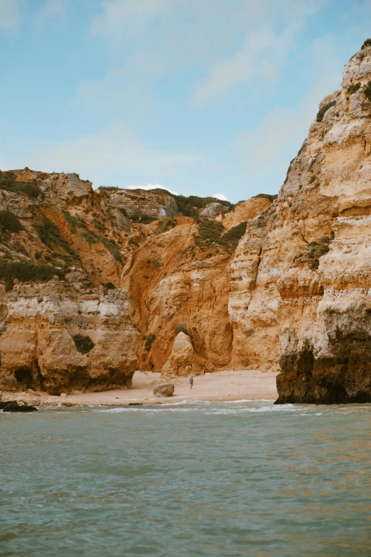 a group of cliffs sitting on the beach near a body of water