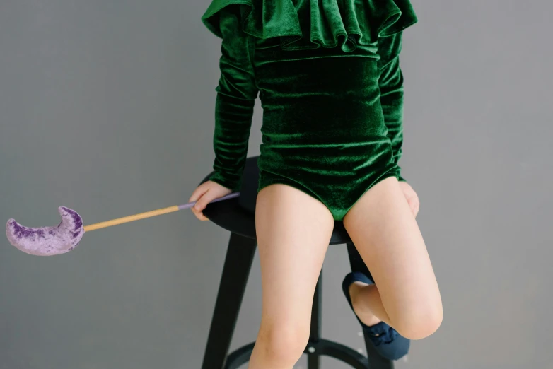 a small child sitting on top of a chair next to a purple umbrella