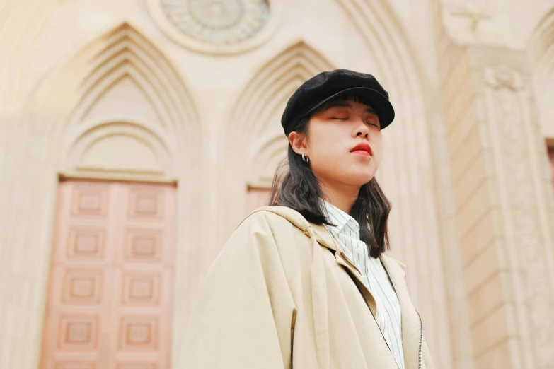 a girl in a black hat and trench coat and the cathedral