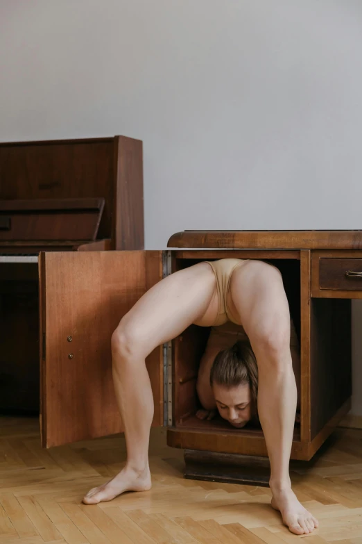 a woman in a brown underwiret is crawling up in a cabinet