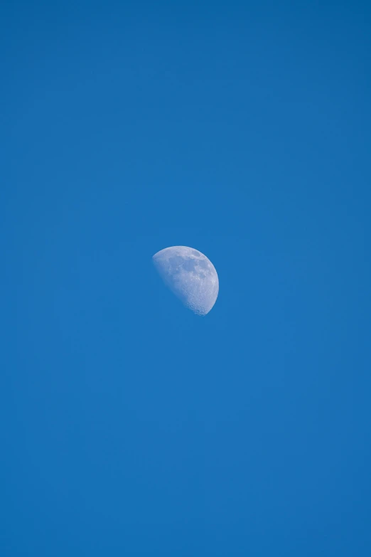 the moon is visible in a bright blue sky