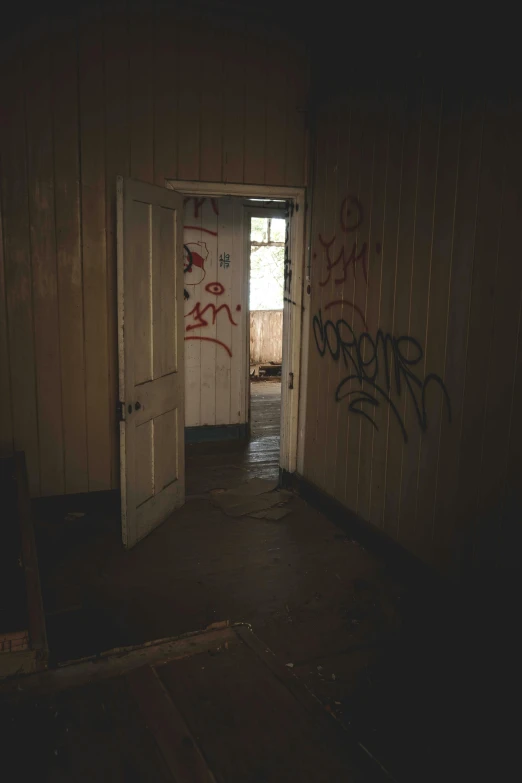 doorway with graffiti writing across it and open door to another room