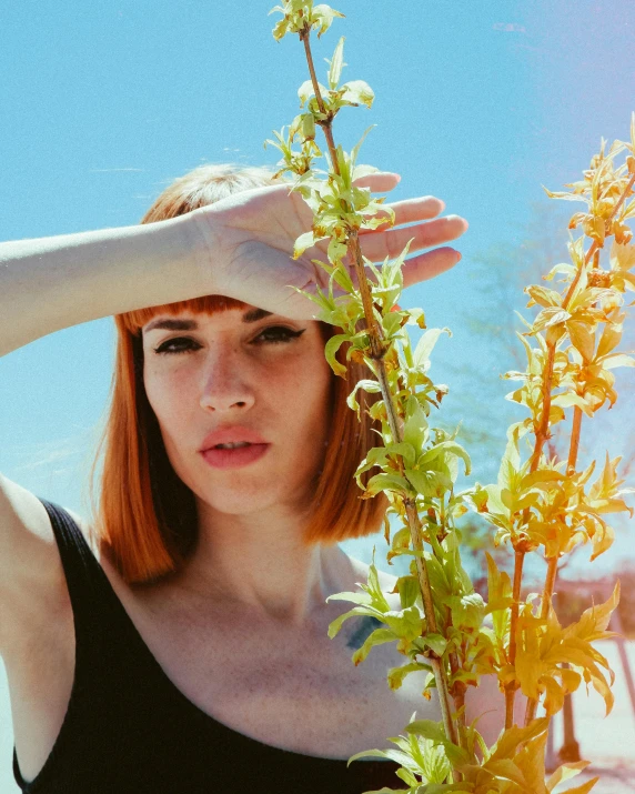 the woman holds up a plant on a sunny day