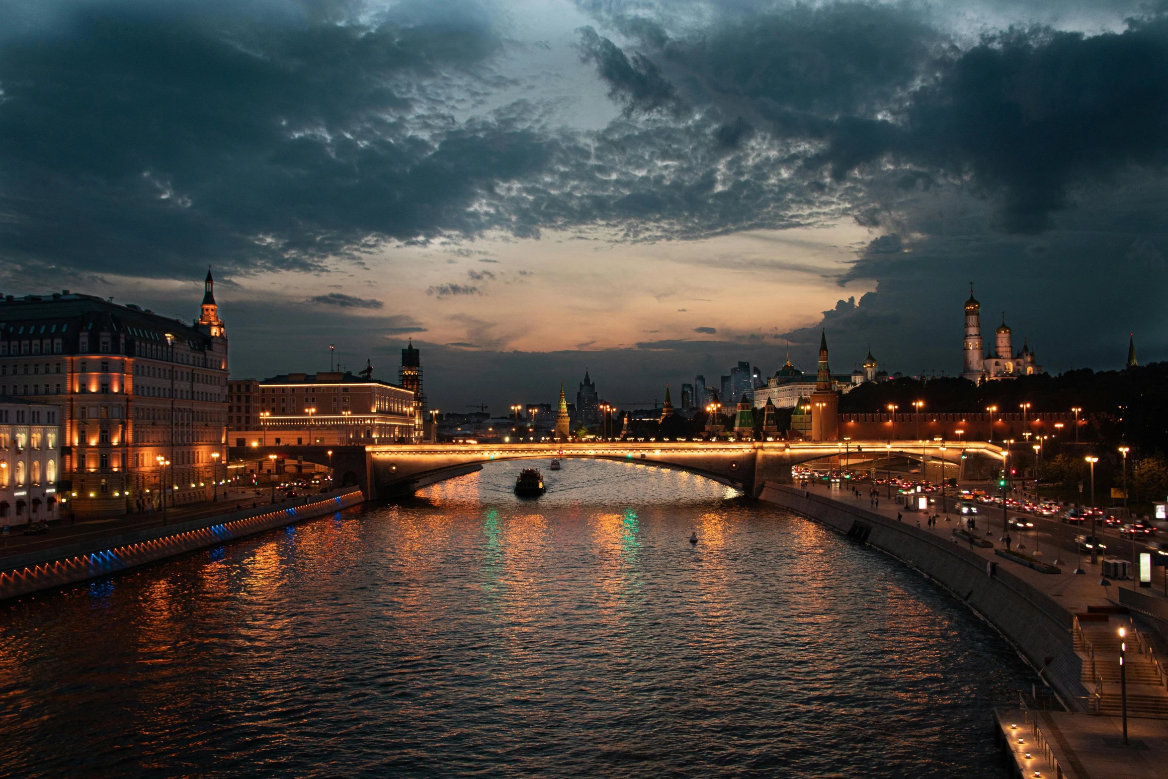 a view of a bridge, some people and a boat at night