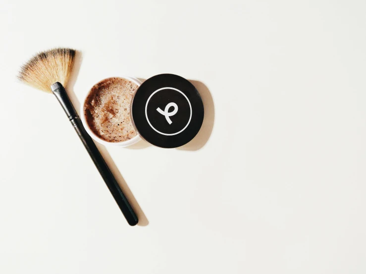 two brushes next to a powder container with a powder on it