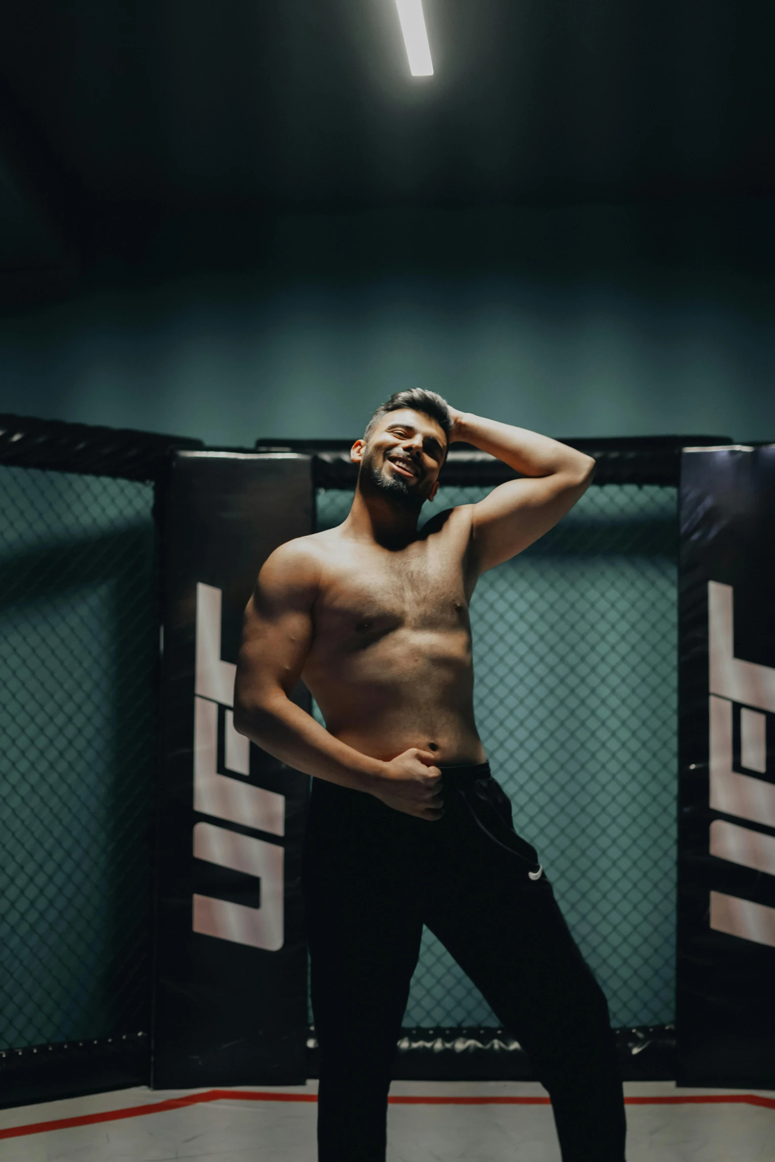 a shirtless man poses for a po in an empty gym