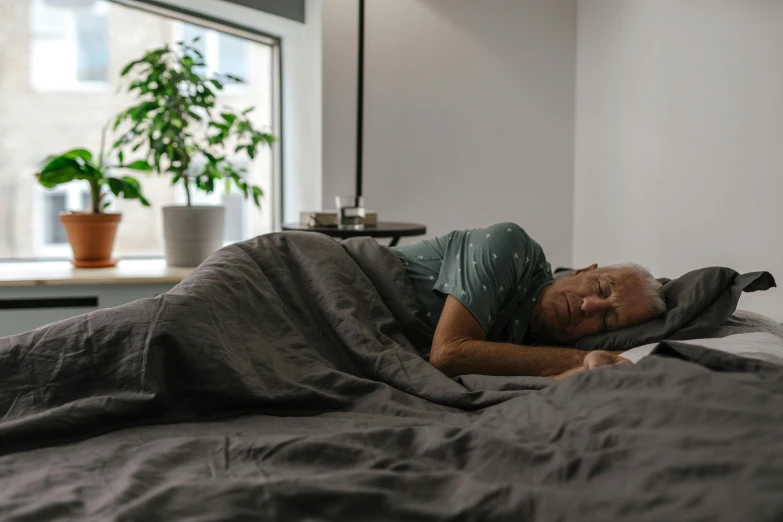 a person lays down and covers himself on a bed