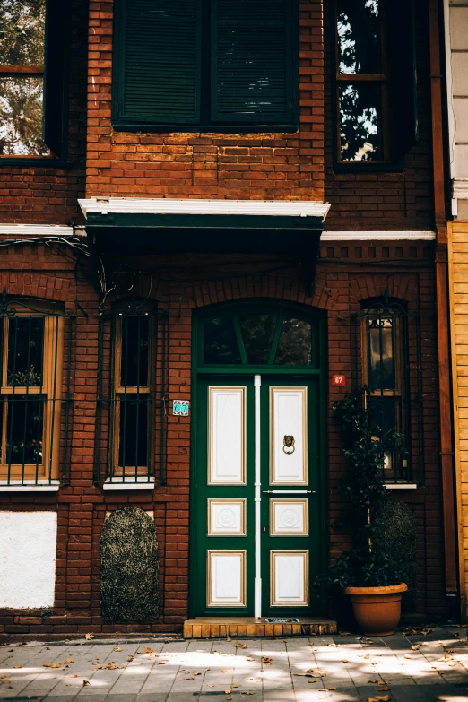 a picture of a brown house and two green doors