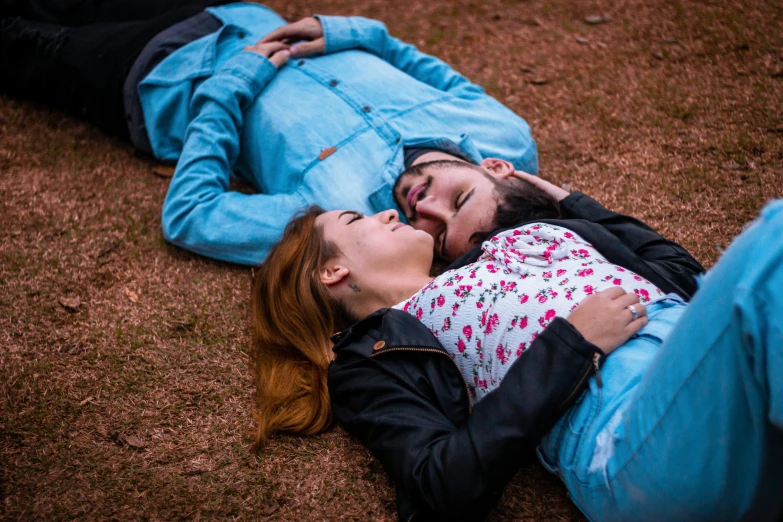 a woman and man are laying on the ground together