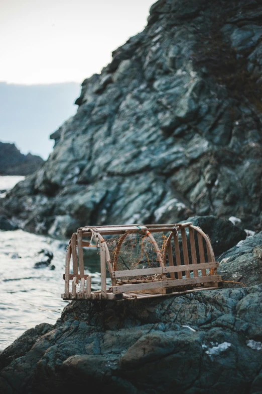 an old wooden bench sitting on a rock by the water