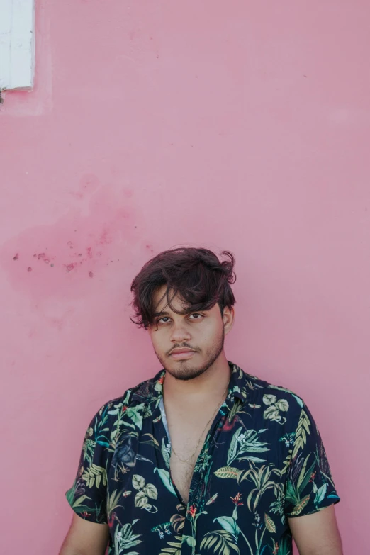 a man is standing against a pink wall