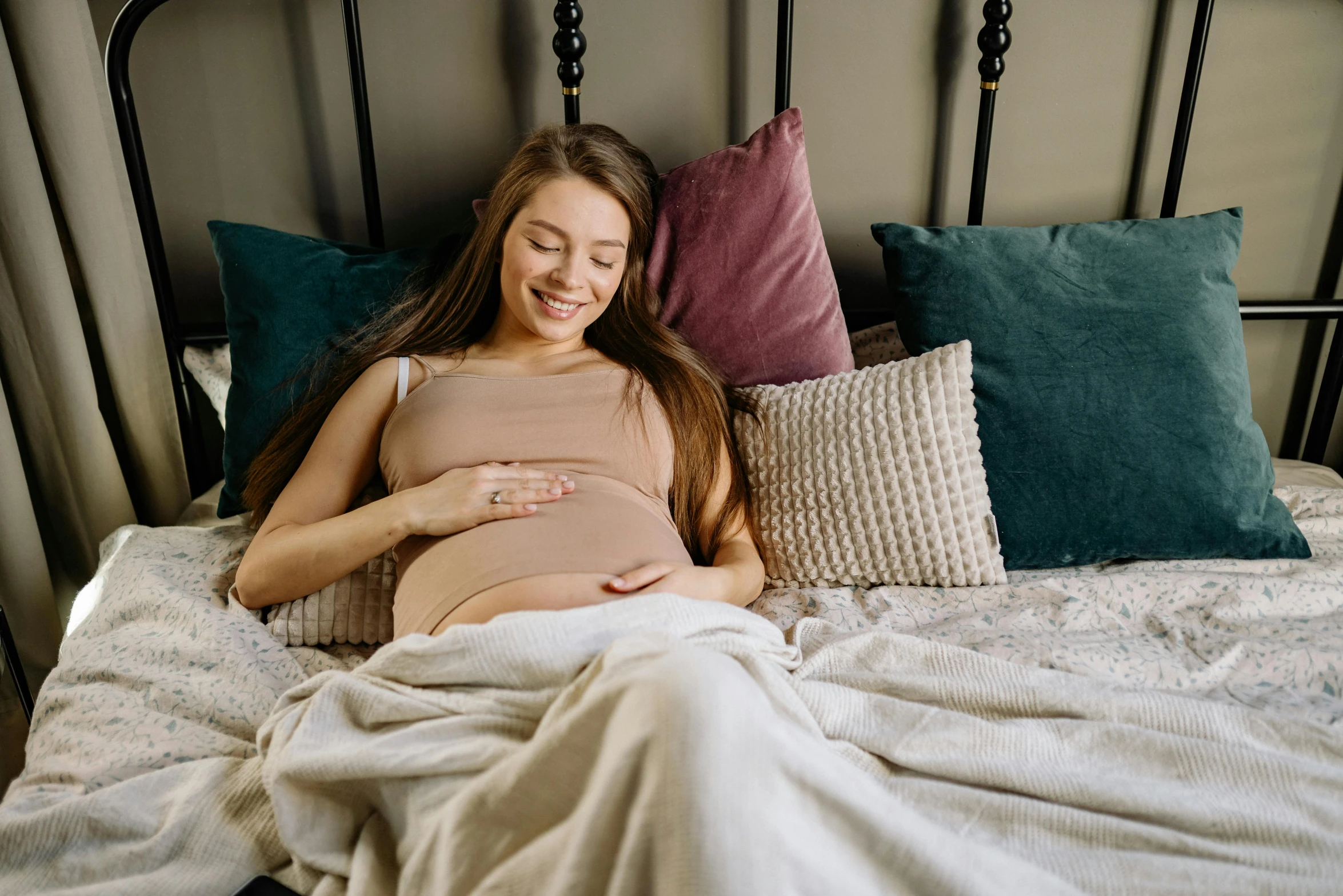 a pregnant girl laying on her stomach on a bed