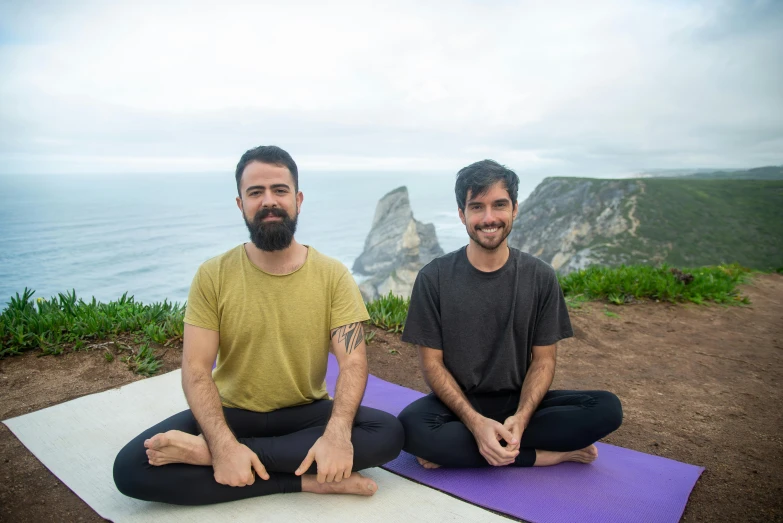 two men in front of the ocean doing yoga on mats