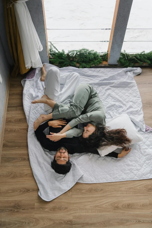 a few people laying on a white blanket