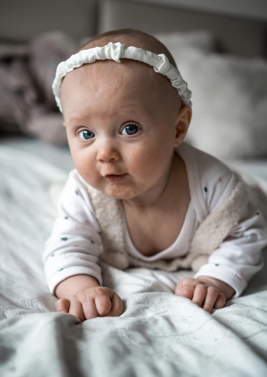 an adorable baby girl with a pretty hair bow on her head