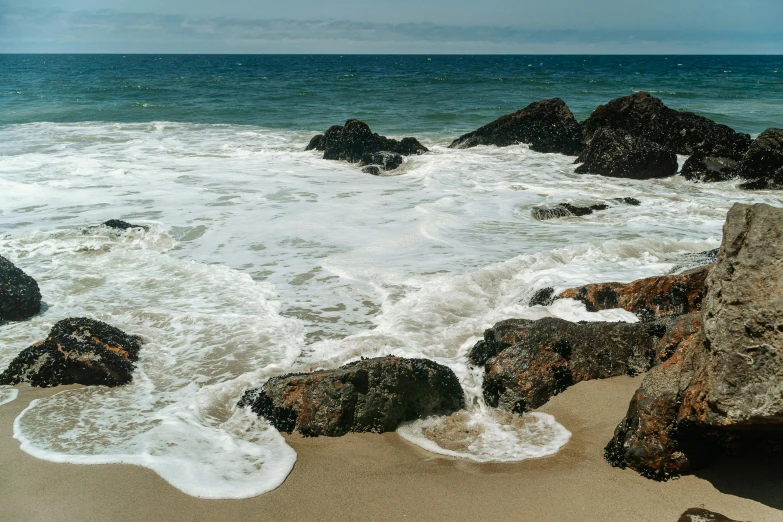 a beach with several rocks sticking out of the ocean