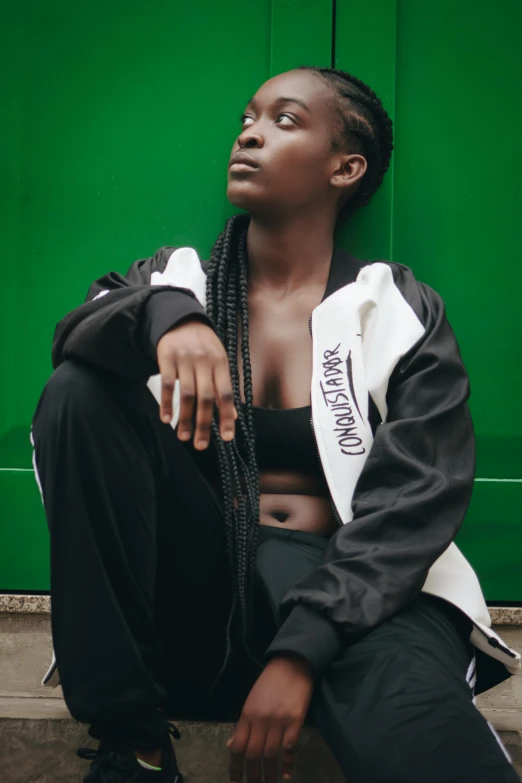 a black man sitting on the ground by a wall