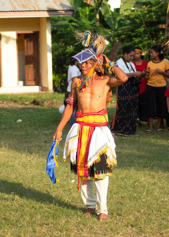 a young man in colorful clothing standing with people watching