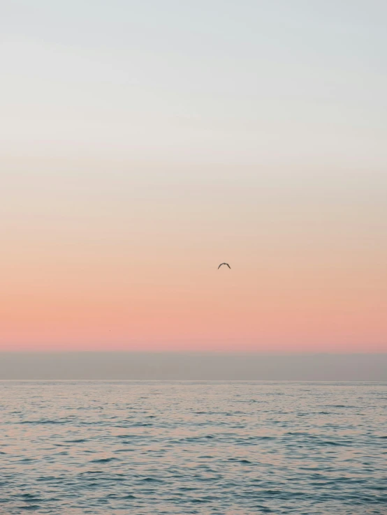 two birds fly across the colorful sky above the water