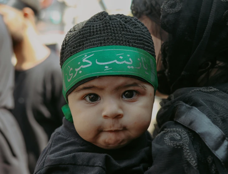 a small child with a green bandana and hat