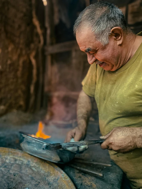 a man with glasses holds soing and looks at the orange flame he is placing in his hand