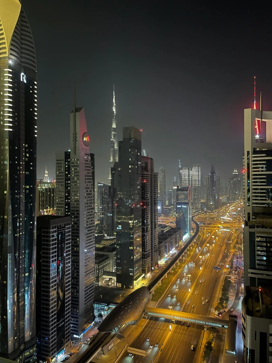 a night view shows a city street with traffic, a bus stop and a busy highway