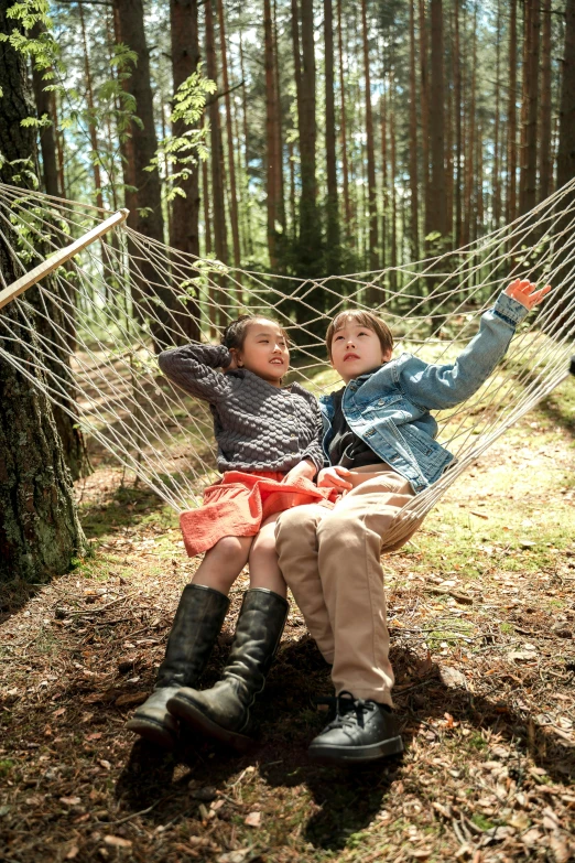 two children sitting in a hammock in the woods