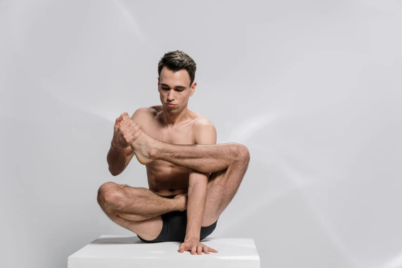 man sitting on white box with hands clasped