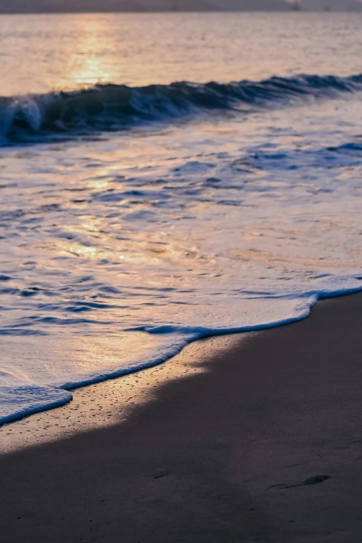 sunset over an ocean with a beach wave crashing into the shore