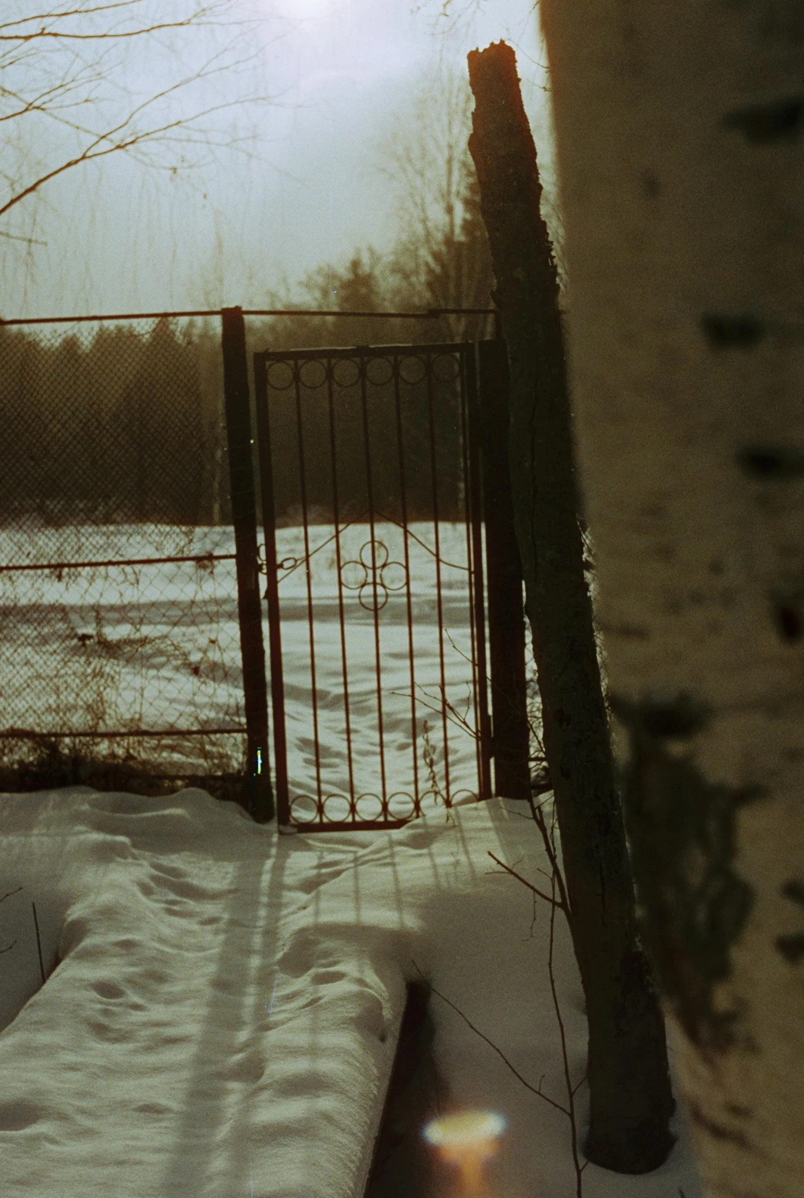 a fence covered in snow in front of a snowy field