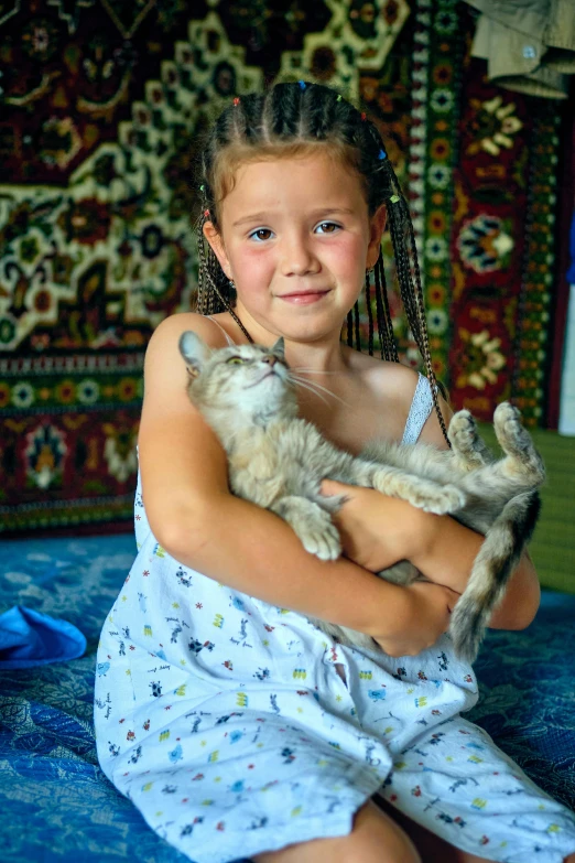 a small girl holding her cat in a blue blanket