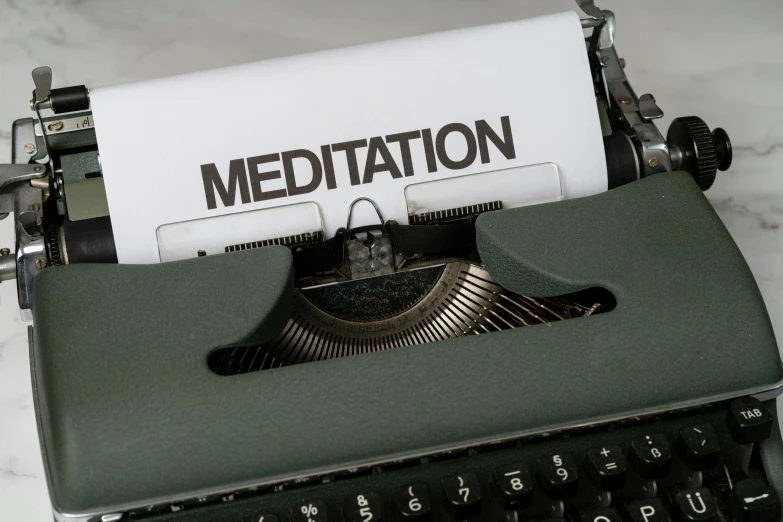 a close up of a green typewriter with the word meditation on it