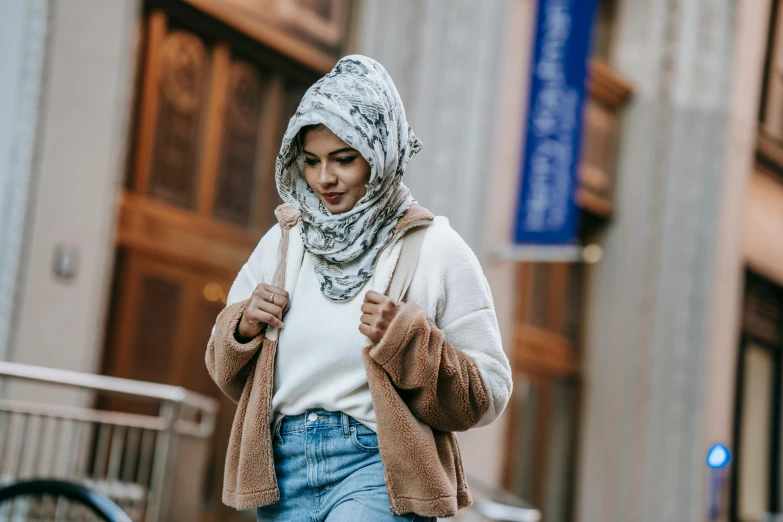 a woman is wearing a headscarf and is walking down the street