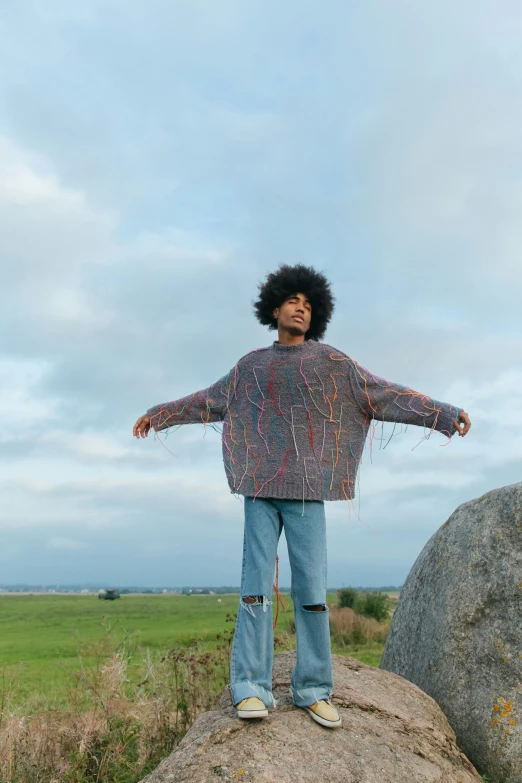 a man standing on top of a rock on top of a green field