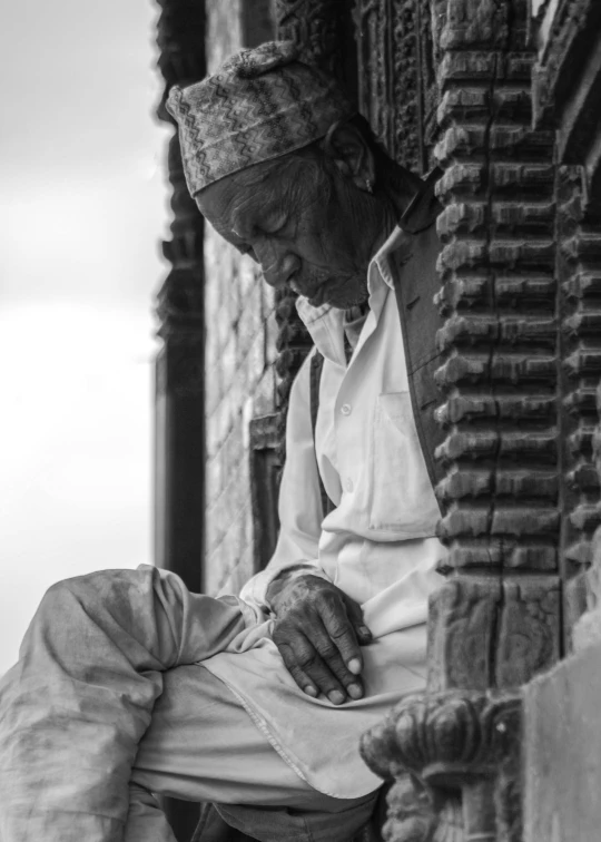 a man is sitting on the ledge with a white blanket