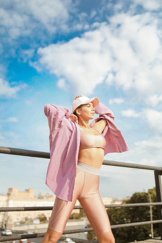 a woman standing on a rooftop wearing a pink bikini top and matching pants