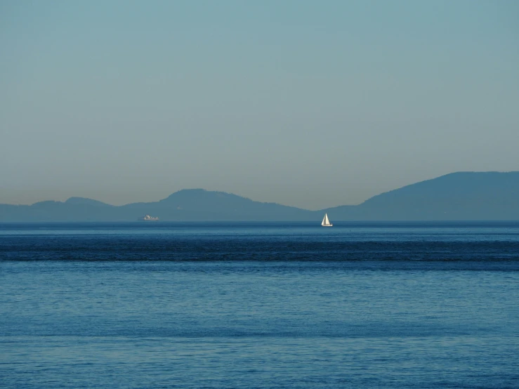 a large body of water with a sail boat floating in it