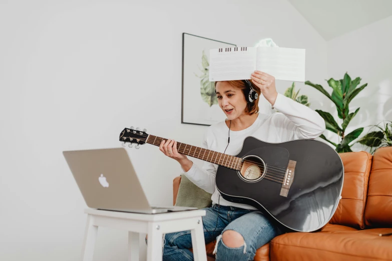 the woman is wearing a paper crown and playing the guitar