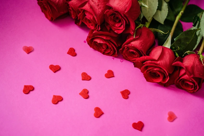 red roses are surrounded by small hearts on pink background