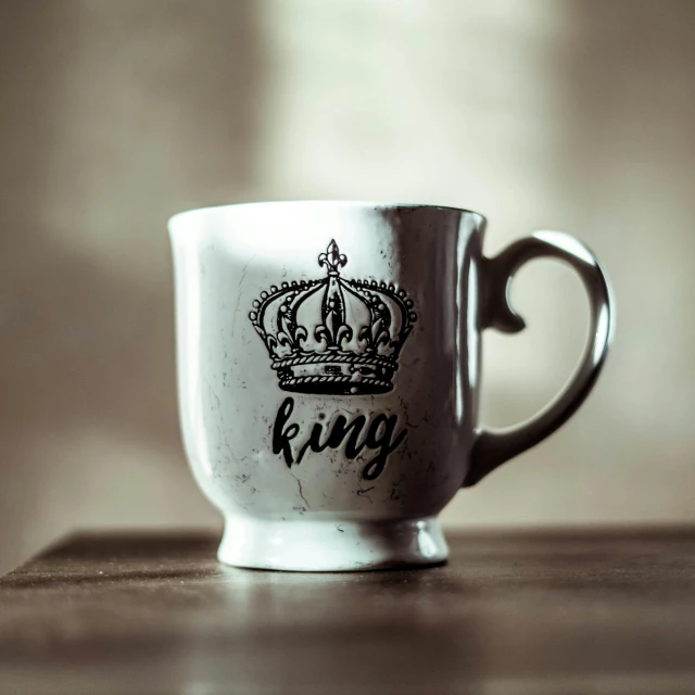 a white cup with a black crown imprint on the side