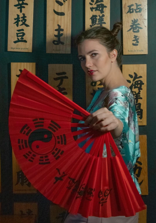 the woman holds up an oriental fan in front of many signs