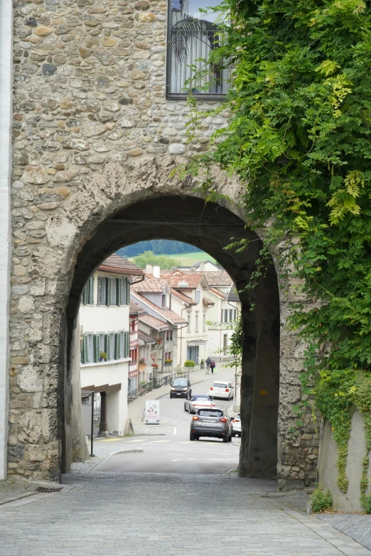 an arched stone building with traffic at the end