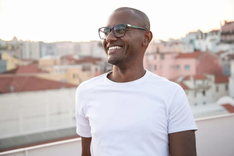 a man wearing sunglasses smiles on top of a roof