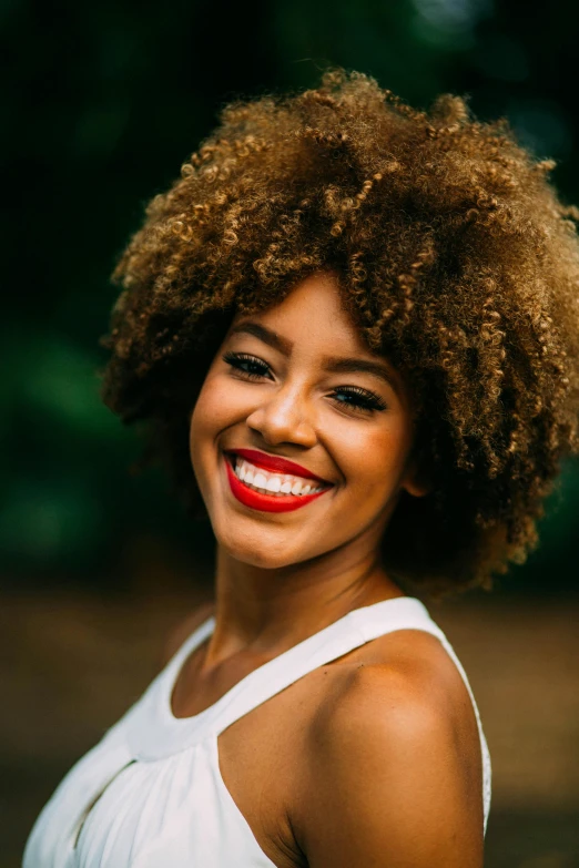 woman smiling, wearing an afro, with natural hair